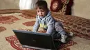 Bayi laki-laki berusia 18 bulan yang bernama Donald Trump bermain dengan laptop di rumah kontrakannya di Kabul, Kamis (15/3). Dengan menamai anaknya dengan nama Trump, Assadullah berharap putranya bisa meraih kesuksesan dalam hidup. (AP/Rahmat Gul)