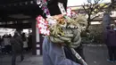 Seorang pengunjung membawa "kumade", atau jimat keberuntungan berbentuk penggaruk untuk bisnis di dekat kuil Kawasaki Daishi, di mana banyak pengunjung berdoa memohon keberuntungan selama "hatsumode" atau kunjungan pertama di tahun itu ke kuil atau kuil, di Kawasaki, dekat Tokyo, Senin, 2 Januari 2023. (AP Photo/Eugene Hoshiko)