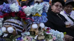 Para wanita duduk di samping tengkorak yang dihias di luar pemakaman umum selama festival tahunan "Natitas" di La Paz, Bolivia, Senin (8/11/2021). Warga ramai-ramai menghias tengkorak leluhur mereka dengan berbagai dekorasi mulai dari bunga, topi, kacamata dan hiasan lainnya. (AP Photo/Juan Karita)