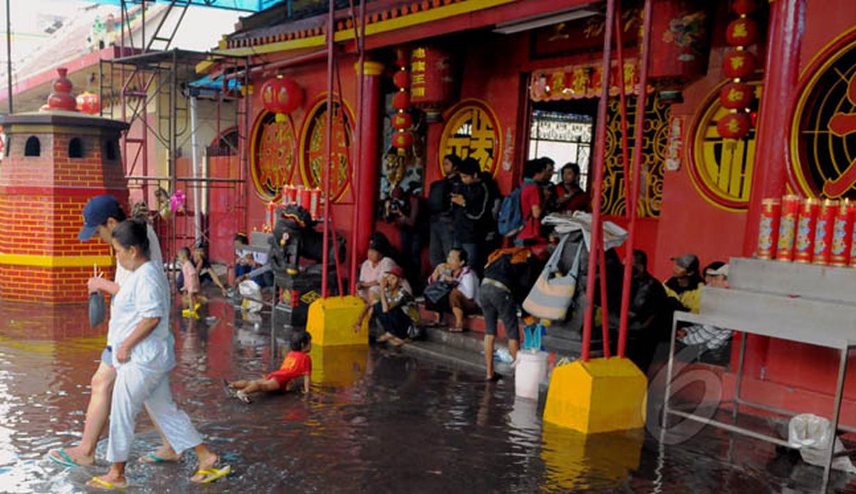 Masyarakat Tionghoa melintasi genangan air di Vihara Dharma Bakti, Petak Sembilan, Jakarta, Kamis (19/2/2015). Hujan deras yang mengguyur kawasan tersebut sekitar pukul 11.30 WIB membuat halaman depan vihara tergenang. (Liputan6.com/Andrian M Tunay)