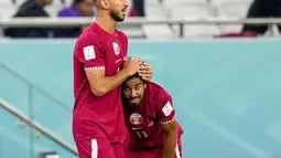 Gelandang Qatar, Mohammed Waad memeluk rekan setimnya Akram Afif setelah kalah 1-3 dari Senegal dalam pertandingan grup A Piala Dunia di Stadion Al Thumama di Doha, Qatar, Jumat, 25 November 2022. 'The Maroon' juga jadi tuan rumah pertama dalam sejarah Piala Dunia yang tereliminasi usai main dua laga. (AP Photo/Petr Josek)