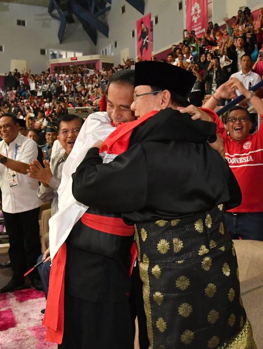 Presiden Joko Widodo atau Jokowi dan Ketua Umum Pengurus Besar Ikatan Pencak Silat Indonesia (IPSI) Prabowo Subianto memeluk atlet pencak silat peraih emas Asian Games 2018 Hanifan Yudani di Jakarta, Rabu (29/8). (Liputan6.com/HO/Biro Pers Setpres)