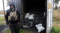 Seorang pasukan khusus Irak berdiri dekat kontainer berisi gas mustard yang ditemukan di sebuah gudang senjata di sisi timur Mosul, Sabtu (28/1). Pihak berwenang mengatakan bahwa gudang senjata itu milik kelompok militan ISIS. (AP Photo/Khalid Mohammed)
