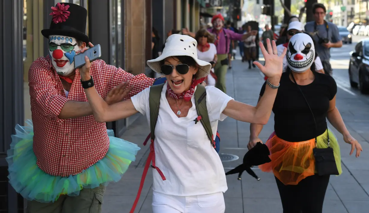 Para peserta berdandan seperti badut mengejar pejalan kaki selama 'Running of the Clowns' di Pasadena, California pada 21 Oktober 2018. Lari dikejar kawanan badut ini merupakan parodi yang mengolok-olok lomba dikejar banteng di Spanyol. (Mark RALSTON/AFP)