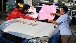 Karyawan Hotel Alexis menempelkan poster tuntutan di mobil Satpol PP saat unjuk rasa di Jakarta Utara, Kamis (29/3). Penutupan terkait kasus dugaan adanya praktek prostitusi dan perdagangan manusia di hotel tersebut. (Liputan6.com/Immanuel Antonius)