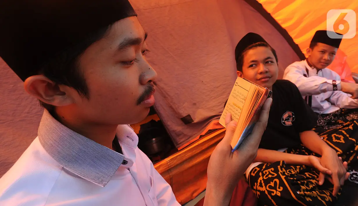 Santri membaca Al-Qur'an saat kegiatan Kemah Hari  Santri di Bogor, Selasa (22/10/2019). Pemerintah menetapkan 22 Oktober sebagai HSN bertepatan dengan Resolusi Jihad yang dikumandangkan  pendiri Nahdlatul Ulama KH. Hasyim Asyari untuk mempertahankan kemerdekaan RI. (merdeka.com/Arie Basuki)