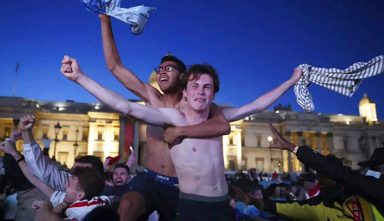 Fans di Trafalgar Square merayakan gol kedua Inggris, yang dicetak oleh Harry Kane, saat mereka menonton pertandingan semifinal Euro 2020 antara Inggris dan Denmark di layar lebar, di London, Inggris (8/7/2021). (Kirsty O'Connor/PA via AP)