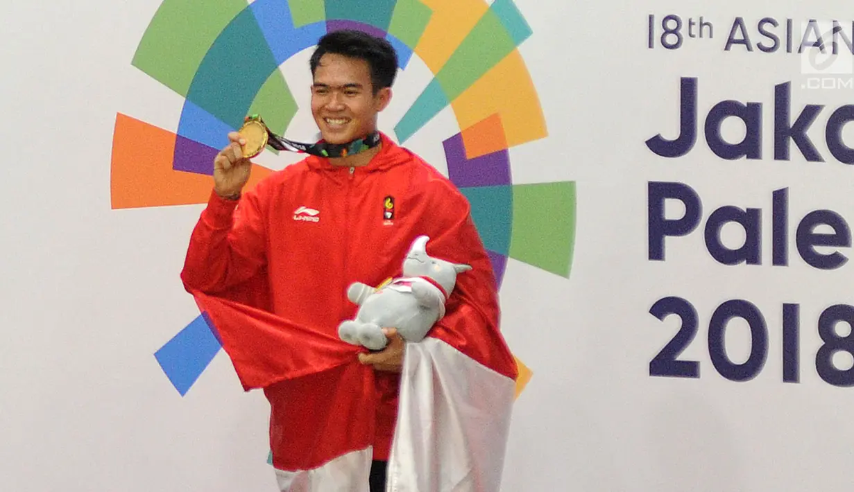 Pesilat Indonesia, Komang Harik Adi Putra menunjukkan medali emas usai memenangkan final Kelas E Putra Asian Games 2018, Jakarta, Senin (27/8). Komang menyumbang emas ke-17 Indonesia di Asian Games 2018. (Merdeka.com/Arie Basuki)