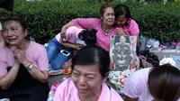 Warga berkumpul di Rumah Sakit Siriraj sambil membawa gambar Raja Thailand Bhumibol Adulyadej di Bangkok, Thailand, Kamis (13/10). Mereka datang karena khawatir akan kondisi kesehatan sang Raja dan berusaha mendoakannya. (REUTERS / Chaiwat Subprasom)
