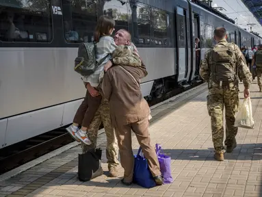 Seorang prajurit Ukraina memeluk istri dan putrinya di stasiun kereta api di Sloviansk, wilayah Donetsk, Ukraina pada Selasa, 12 September 2023. (AP Photo/Hanna Arhirova)