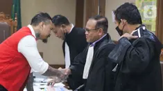 Terdakwa yang juga musisi I Gede Ari Astina atau Jerinx SID bersalaman dengan kuasa hukum usai menjalani sidang lanjutan kasus pengancaman melalui media elektronik pada Adam Deni di Pengadilan Negeri (PN) Jakarta Pusat, Jakarta, Senin (14/2/2022). (Liputan6.com/Herman Zakharia)