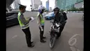 Petugas kepolisian menilang seorang pengendara motor yang menerobos Jalan MH Thamrin, Jakarta, Minggu (18/1/2015). (Liputan6.com/Miftahul Hayat)