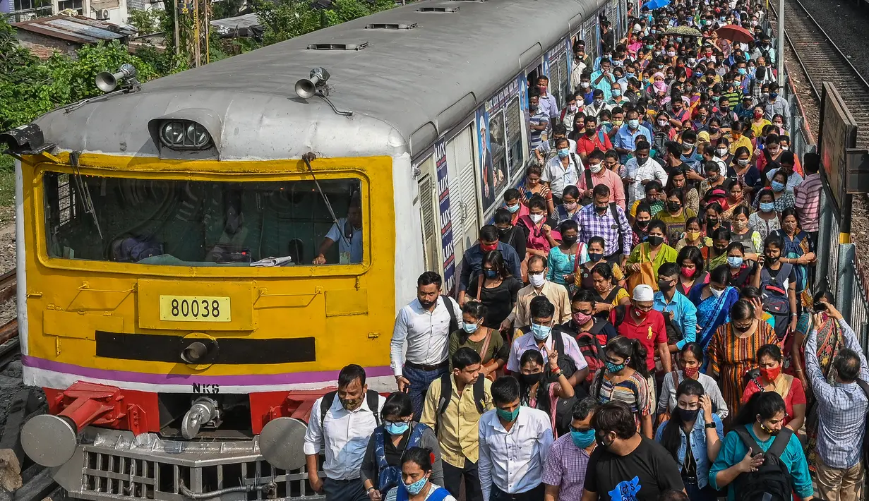Komuter berjalan di sepanjang peron setelah keluar dari kereta lokal pinggiran kota di Kolkata, India, Senin (1/11/2021). Layanan kereta api kembali normal setelah menerapkan pembatasan yang diberlakukan sebelumnya untuk mengekang penyebaran corona Covid-19. (DIBYANGSHU SARKAR/AFP)