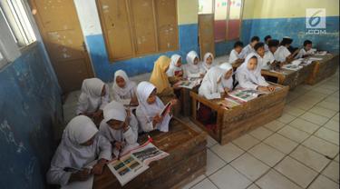 Murid-murid kelas V melakukan kegiatan belajar pada meja yang diubah menjadi kursi dan tempat belajar di SDN Kertajaya 2, Rumpin, Bogor (22/7/2019). Sudah lebih dari tiga tahun mereka belajar  pada fasilitas yang minim. (merdeka.com/Arie Basuki)