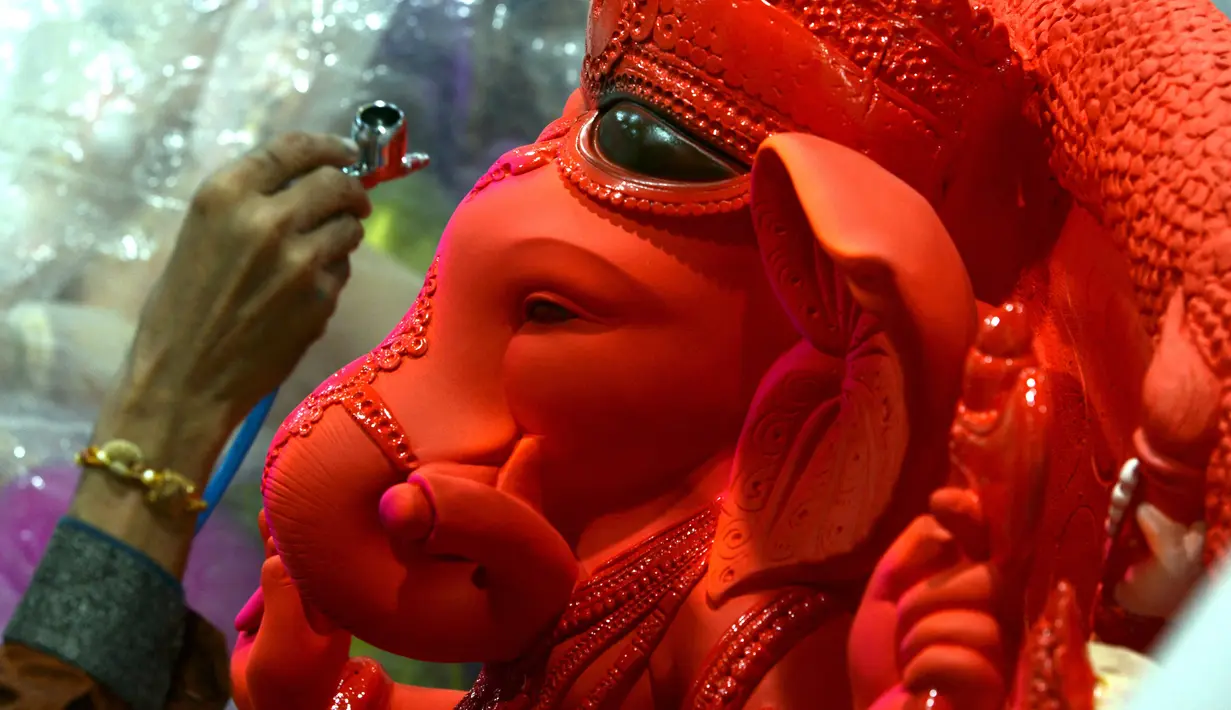 Seorang perajin mengerjakan pembuatan patung Dewa Ganesha di sebuah bengkel di Mumbai, India, 24 Agustus 2021. Pembuatan patung dewa Hindu berkepala gajah tersebut dilakukan jelang Festival Ganesh Chaturthi. (SUJIT JAISWAL/AFP)