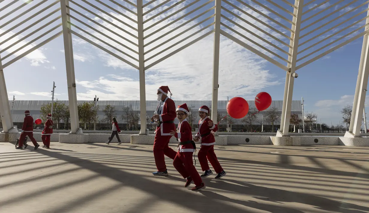 Orang-orang dengan kostum Sinterklas berlari di jalan setapak dari kubah baja, yang disebut Agora, selama Athens Santa Run di Athena, Yunani, Minggu (12/12/2021). Ratusan orang mengikuti lomba lari untuk acara amal di area sekitar kompleks Stadion Olimpiade Athena. (AP Photo/Yorgos Karahalis)