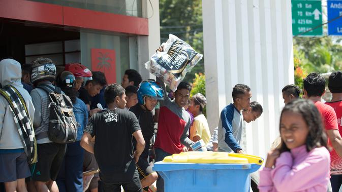 Warga menjarah kebutuhan pokok dari toko swalayan setelah gempa kuat dan tsunami mengguncang Kota Palu di Sulawesi Tengah, Minggu (30/9). Warga terpaksa mengambil karena mereka juga membutuhkan makanan dan air bersih. (AFP PHOTO/BAY ISMOYO)