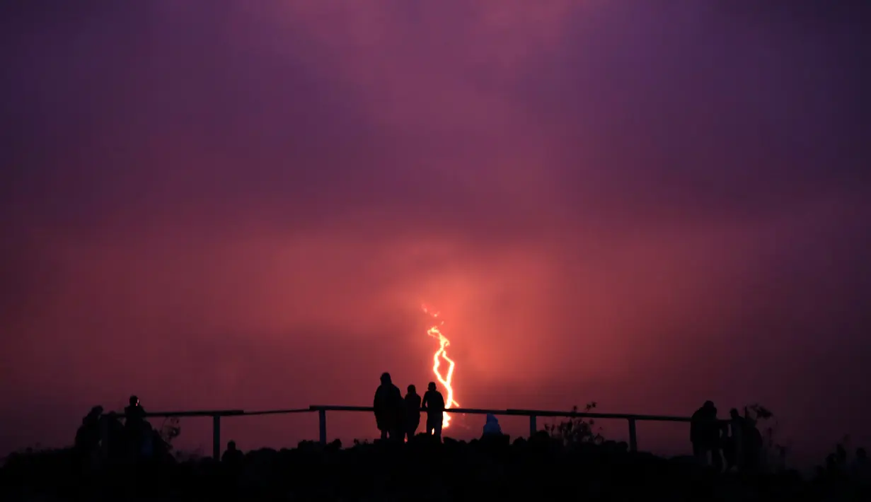 Warga melihat guguran lava pijar yang keluar dari gunung api Piton de la Fournaise atau Peak of the Furnace di Pulau Reunion, Samudera Hindia, Prancis, Selasa (13/8/2019). Letusan Piton de la Fournaise berlanjut hingga hari ketiga. (Richard BOUHET/AFP)
