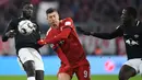 Striker Bayern Munich, Robert Lewandowski, berusaha melewati pemain RB Leipzig pada laga Bundesliga di Allianz Arena, Kamis (20/12). Bayern Munich menang 1-0 atas RB Leipzig. (AFP/Chirstof Stache)