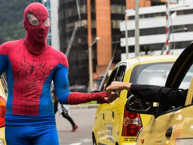 Jahn Fredy Duque menerima uang usai aksi di jalanan Bogota, Kolombia, Senin (24/4). Duque mencari nafkah dengan melakukan atraksi layaknya Spiderman. (AFP Photo/RAUL ARBOLEDA)