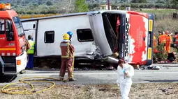 Petugas darurat dikerahkan ke lokasi kecelakaan sebuah bus berisi mahasiswa asing di Jalan Raya AP7 dekat Kota Freginals, Spanyol, Minggu (20/3). Sedikitnya 13 penumpang tewas dalam insiden itu sementara puluhan lainnya luka-luka. (PAU Barrena/AFP)
