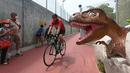 Pengendara sepeda bersepeda di sepanjang "Changi Jurassic Mile" jalur rekreasi dengan jajaran model dinosaurus seukuran aslinya di Singapura (13/10/2020). Atraksi rekreasi baru dengan pameran dinosaurus yang menghubungkan terminal Bandara Changi 4 dan taman East Coast. (AFP/Roslan Rahman)