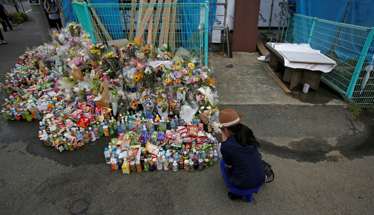 Seorang wanita berdoa untuk orban Penikaman Massal yang terjadi di Kawasaki, Jepang (29/5/2019). Korban tewas dalam penikaman ini bertambah menjadi dua orang. Pelaku sendiri tewas usai menikam dirinya. (Reuters/Issei Kato)