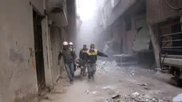 Anggota Syrian Civil Defense yang dikenal dengan White Helmets membawa korban luka dalam serangan udara pemerintah Suriah di Ghouta, pinggiran kota Damaskus, Suriah, Jumat (23/2). (Syrian Civil Defense White Helmets via AP)