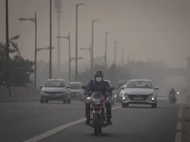Seorang pengendara sepeda motor berkendara dengan menggunakan masker polusi di tengah kabut asap di New Delhi, India, Selasa (7/11/2023). (AP Photo/Altaf Qadri)