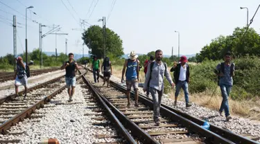 Sejumlah imigran berjalan menyusuri rel kereta api saat perjalanan menuju Gevgelija, wilayah perbatasan Macedonia-Yunani, Kamis (9/7/2015). Mereka menempuh ribuan kilometer agar dapat mengejar kereta api tujuan Serbia. (AFP PHOTO/Robert ATANASOVSKI)