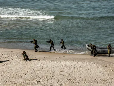 Pejuang bersenjata turun dari perahu karet di pantai selama latihan militer di Kota Gaza (29/12/2020).  Untuk pertama kalinya, Hamas bersama sayap militer kelompok-kelompok perlawanan Palestina lainnya menggelar latihan perang gabungan. (AFP/Mohammed Abed)