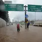 Seorang pria menyusuri banjir yang menggenangi Jalan Tol JORR di kawasan TB Simatupang, Jakarta Selatan, Sabtu (20/2/2021). Banjir terjadi akibat luapan Kali Serua yang berada di pinggir jalan tol. (merdeka.com/Arie Basuki)