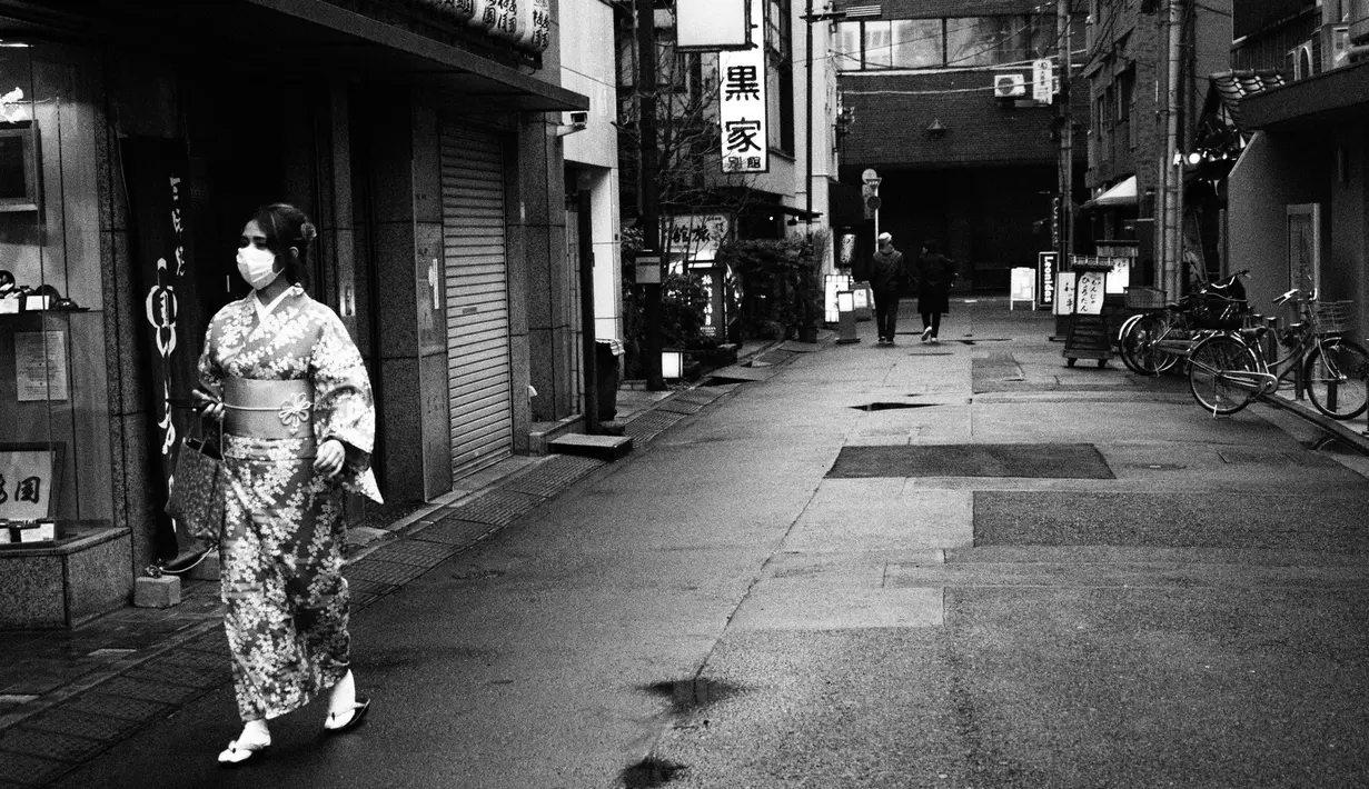 Seorang wanita mengenakan kimono berjalan melewati toko-toko suvenir di Tokyo, (8/3/2020). (AP Photo/Jae C. Hong)