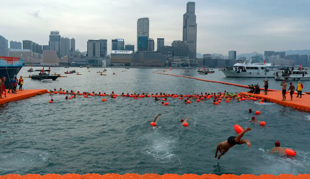 Perenang melompat ke dalam air saat mengikuti lomba renang tahunan di Pelabuhan Victoria, Hong Kong, Minggu (23/10/2022). (AP Photo/Anthony Kwan)