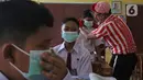 Seniman Aku Badut Indonesia (ABI) memasangkan masker kepada siswa di SDN 03 Citayam, Kabupaten Bogor, Jawa Barat, Senin (6/9/2021). Aksi tersebut tentang protokol kesehatan serta membagikan masker kepada anak-anak sekolah yang menggelar Pembelajaran Tatap Muka (PTM). (Liputan6.com/Herman Zakharia)