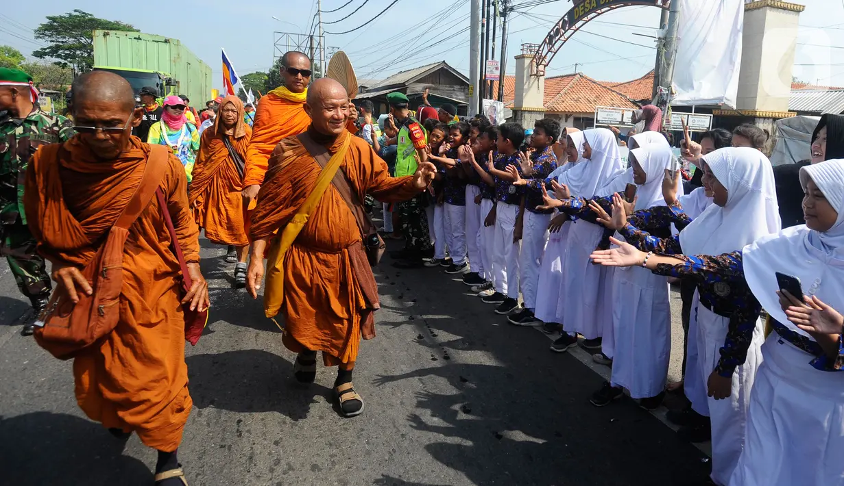 Murid sekolah dasar menyambut perjalanan rombongan 32 Biksu dari berbagai negara yang melakukan ritual Thudong dengan berjalan kaki menuju Candi Borobudur di Wiradesa, Kabupaten Pekalongan, Jawa Tengah, Kamis (25/5/2023). Ribuan warga menyambut perjalanan para biksu di sepanjang Jalan Pantura. (merdeka.com/Arie Basuki)