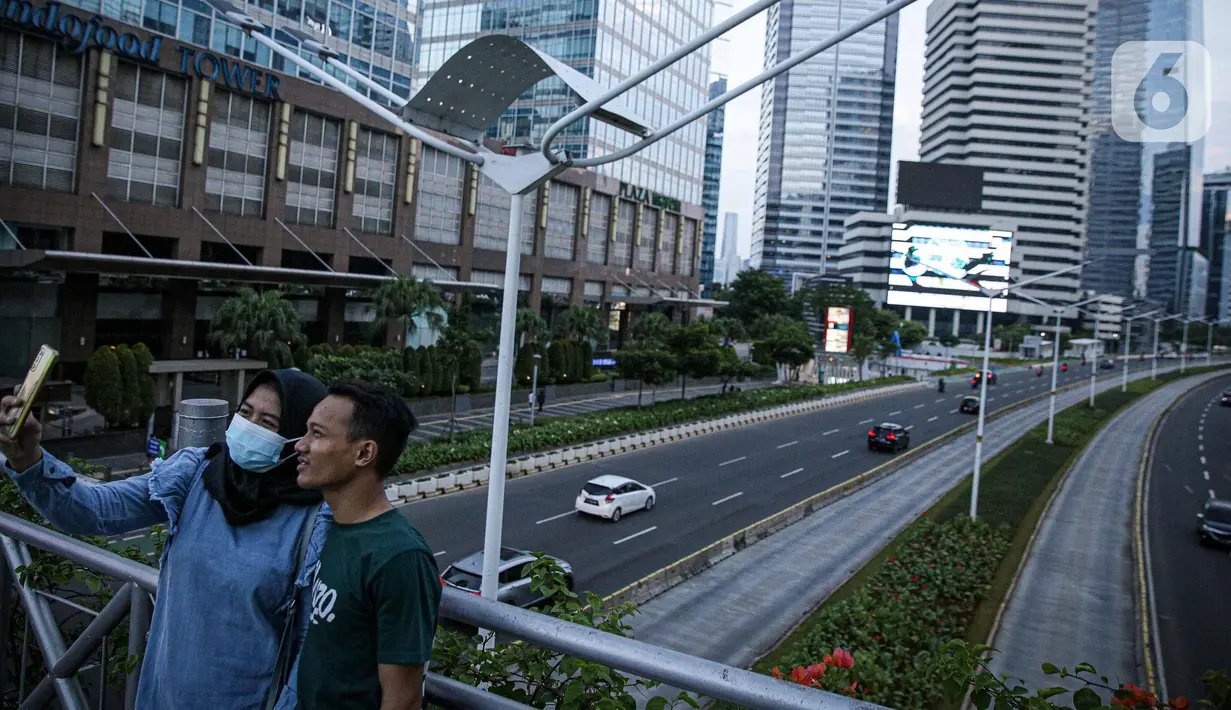 Warga berkumpul diatas JPO tanpa atap di Jakarta, Minggu (12/9/2021). Kasus baru positif Covid-19 di Indonesia per Minggu (12/9) bertambah sebanyak 3.779 kasus Jumlah tersebut membuat total kasus virus corona sejak awal pandemi mencapai 4.167.511 kasus. (Liputan6.com/Faizal Fanani)