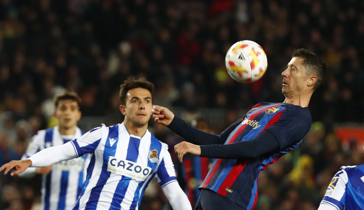 Robert Lewandowski dari Barcelona (kanan) mengontrol bola saat Martin Zubimendi dari Real Sociedad melihatnya selama pertandingan perempatfinal Copa del Rey di stadion Camp Nou, di Barcelona, Spanyol, Kamis (26/1/2023). Barcelona menang tipis atas Real Sociedad dengan skor 1-0. (AP Photo/Joan Monfort)