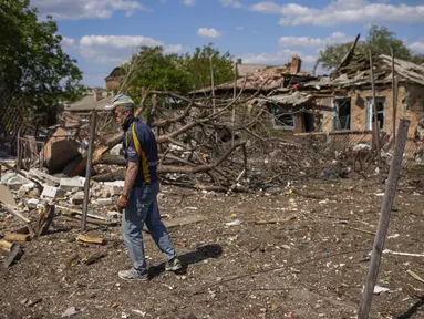 Seorang penduduk setempat berdiri di samping sebuah rumah yang hancur dalam pemboman Rusia di Bakhmut, Ukraina timur, Selasa (24/5/2022). Kota Bakhmut telah mengalami peningkatan serangan artileri, terutama selama seminggu terakhir, ketika pasukan Rusia mencoba untuk terus maju mengepung kota Sieverodonetsk di timur laut. (AP Photo/Francisco Seco)