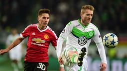 Pemain Manchester United, Guillermo Varela (kiri) berebut bola dengan pemain Wolfsburg, Andre Schuerrle  pada lanjutan Liga Champions di Stadion VfL Wolfsburg Arena, Rabu (9/12/2015) dini hari WIB. (AFP Photo/John Macdougall)