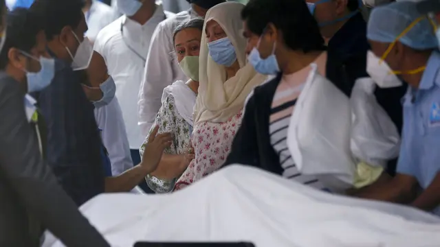 Istri Dilip Kumar, Saira Banu (berkerudung kuning) menangis di sisi jenazah suaminya. (AP Photo/Rafiq Maqbool)
