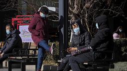 Seorang wanita mengenakan masker untuk melindungi diri dari virus corona berjalan di atas papan yang menampilkan Bing Dwen Dwen, maskot Olimpiade Musim Dingin 2022, di Beijing, Minggu (12/12/2021). (AP Photo/Andy Wong)