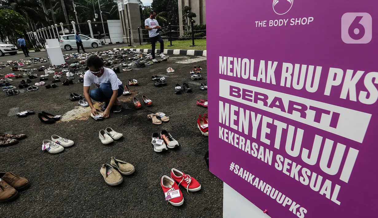 Pegiat komnas perempuan merapikan sepatu saat aksi diam 500 Langkah Awal Sahkan RUU PKS di depan gedung DPR, Jakarta, Rabu (25/11/2020). Dalam aksinya mereka menyusun sepatu sebagai simbol "semua peduli, semua terlindungi, stop sexual violence". (Liputan6.com/Johan Tallo)