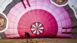 Seorang pilot memeriksa balon udara selama festival tahunan balon udara panas Bristol di Bristol, Inggris (8/8/2019). Festival balon udara ini diadakan selama empat hari dari 8-11 Agustus 2019. (Ben Birchall/PA via AP)