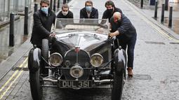 Staf mendorong Bugatti Type 57S 1937, salah satu mobil pra-perang paling diinginkan di dunia, di luar rumah lelang Bonhams,  London, Selasa (16/2/2021). Bugatti ini telah tersembunyi selama 50 tahun terakhir dan merupakan salah satu dari 42 contoh varian 57S yang diproduksi (AP Photo/Frank Augstein)
