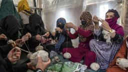 Perempuan Afghanistan menenun wol untuk membuat karpet di pabrik karpet tradisional di Kabul, Afghanistan, Senin  (6/3/2023). Setelah Taliban berkuasa di Afghanistan, banyak hak dasar wanita telah dirampas. (AP Photo/Ebrahim Noroozi)