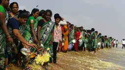 Para wanita melarung bunga persembahan dalam upacara penghormatan untuk korban tsunami tahun 2004 di Pantai Pattinapakkam, Chennai, India, Rabu (26/12). Tsunami Samudra Hindia tersebut dipicu gempa bumi berkekuatan 9,1–9,3 magnitudo. (ARUN SANKAR/AFP)