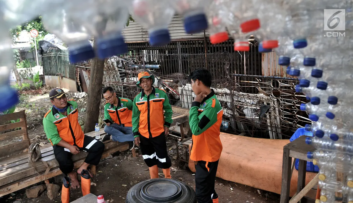 Petugas UPK Badan Air DLH DKI Jakarta berbincang dalam Pos Botol Plastik di Pasar Rebo, Jakarta, Selasa (12/3). Petugas memanfaatkan botol plastik bekas untuk membangun pos cantik. (merdeka.com/Iqbal Nugroho)