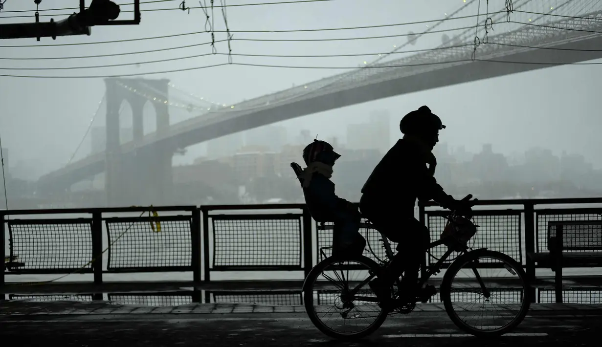 Pengendara sepeda melintasi sepanjang jalan East River Greenway saat badai salju di Manhattan di New York City (7/3). Badai salju kedua yang melanda New York dalam waktu seminggu ini diperkirakan akan membawa angin kencang. (Drew Angerer/Getty Images/AFP)