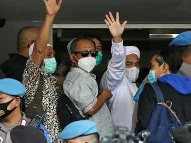Rizieq Shihab (tengah) melambaikan tangan sesaat sebelum masuk gedung utama Mapolda Metro Jaya, Jakarta, Sabtu (12/12/2020). Rizieq Shihab akan menjalani pemeriksan sebagai tersangka penghasutan dan kerumunan di tengah pandemi Covid-19. (Liputan6.com/Helmi Fithriansyah)